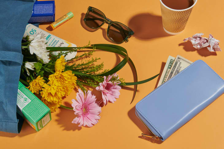   Taška s kvetmi, slnečnými okuliarmi, účtenkou, peňaženkou a šálkou kávy na zlatom pozadí