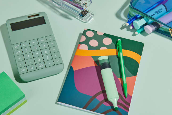   Zelená kalkulačka, zápisník a kancelárske potreby na zelenom pozadí