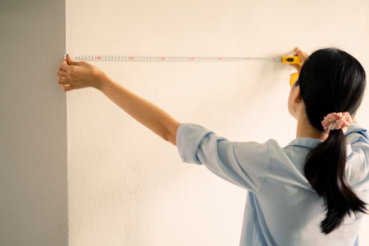   žena meranie steny s krajčírskym metrom