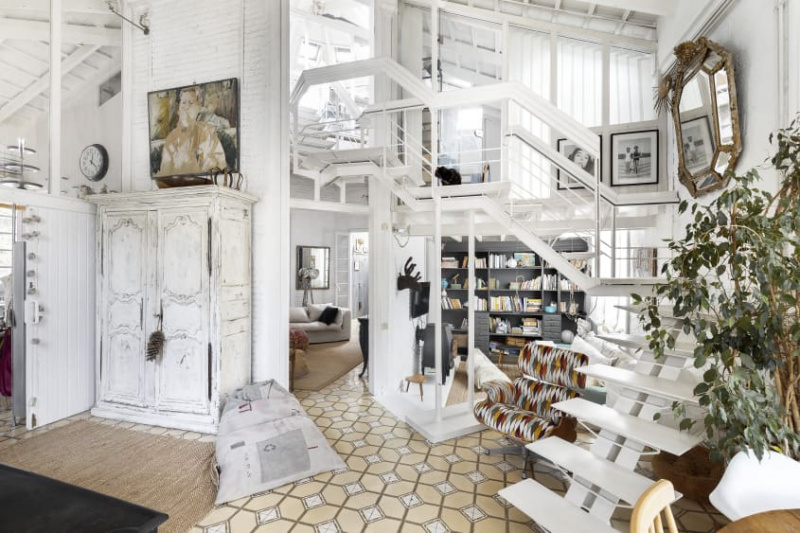 Paredes totalmente brancas e muitas antiguidades reformadas transformam este estúdio de arte convertido em uma casa de família histórica